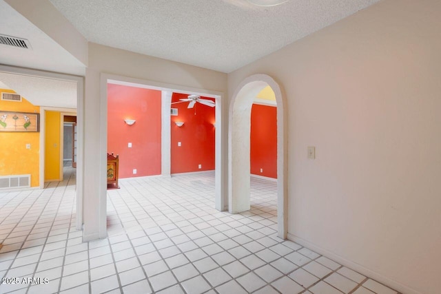 empty room featuring visible vents, a textured ceiling, and a ceiling fan