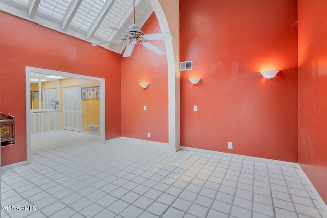 tiled spare room featuring baseboards, a ceiling fan, visible vents, and high vaulted ceiling