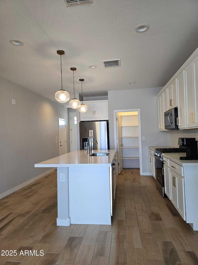 kitchen featuring stainless steel appliances, a sink, visible vents, and white cabinetry