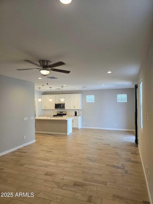 unfurnished living room with light wood-type flooring, ceiling fan, a sink, and recessed lighting