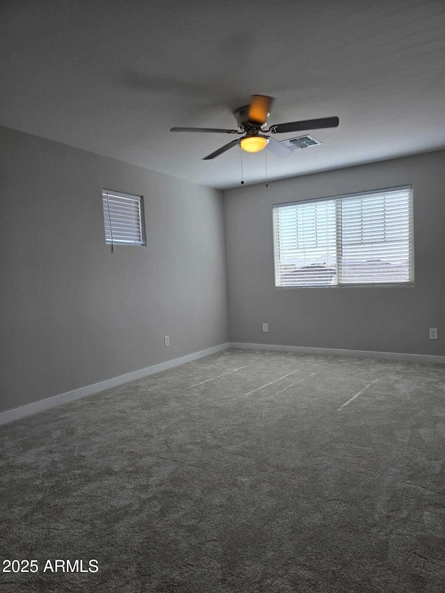 carpeted empty room featuring a ceiling fan, visible vents, and baseboards