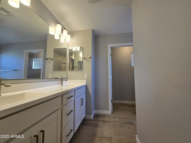 bathroom featuring visible vents, a sink, baseboards, and double vanity
