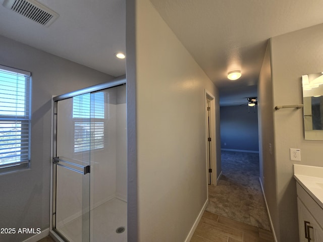 bathroom with a ceiling fan, a stall shower, visible vents, and vanity