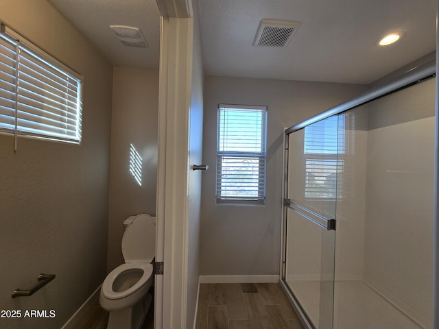 full bath with visible vents, toilet, a stall shower, wood finished floors, and baseboards