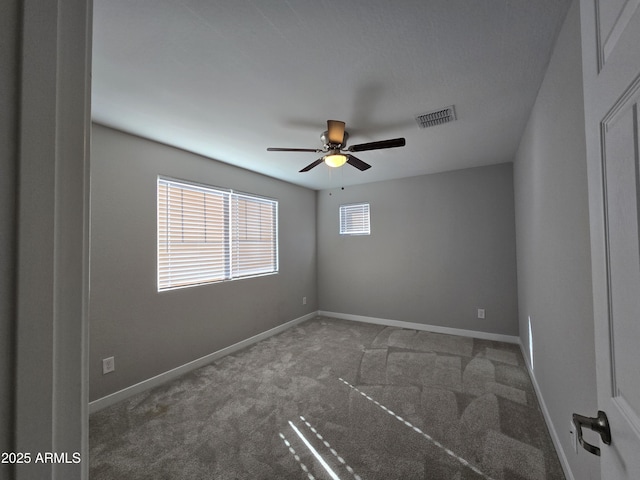 spare room featuring carpet floors, visible vents, baseboards, and a ceiling fan