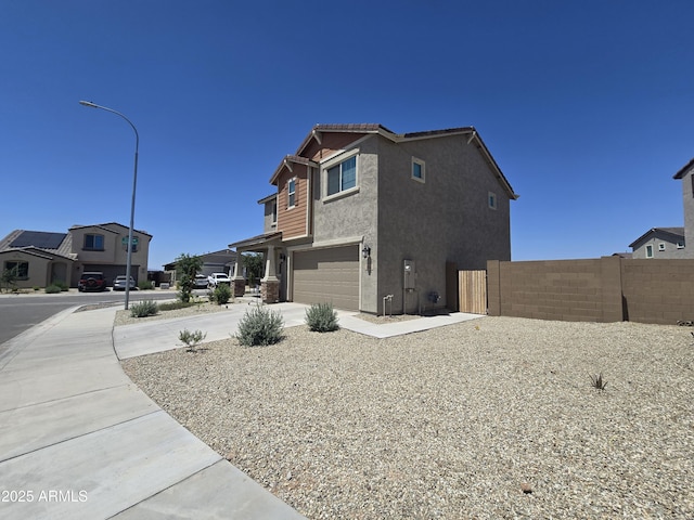 view of property exterior featuring concrete driveway, a residential view, an attached garage, fence, and stucco siding