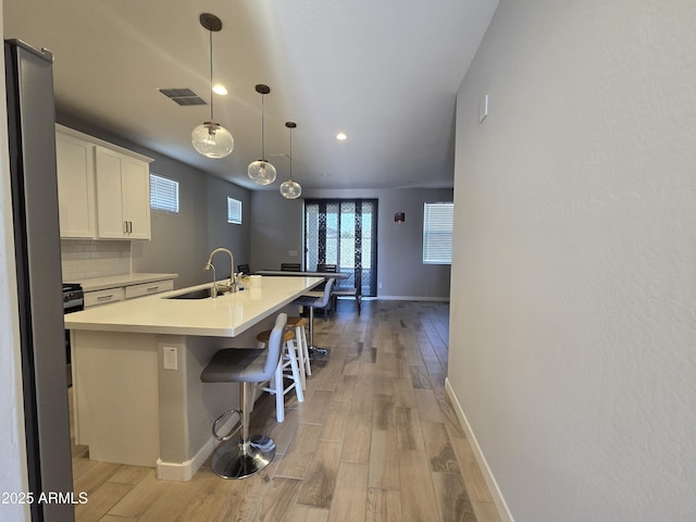 kitchen with light wood finished floors, white cabinetry, decorative backsplash, and a sink