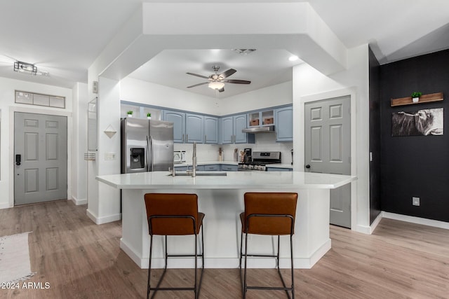 kitchen featuring appliances with stainless steel finishes, a kitchen breakfast bar, ceiling fan, sink, and an island with sink