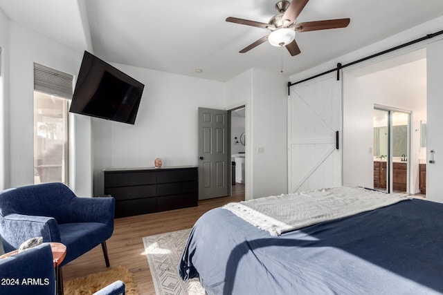 bedroom with hardwood / wood-style floors, ceiling fan, a barn door, and ensuite bath