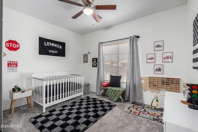 carpeted bedroom with ceiling fan and a crib