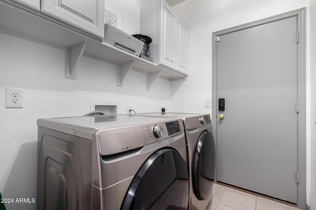 laundry area featuring washer and dryer, cabinets, and light tile patterned floors