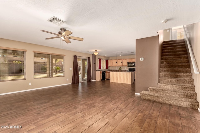 unfurnished living room with ceiling fan, a textured ceiling, and dark hardwood / wood-style floors