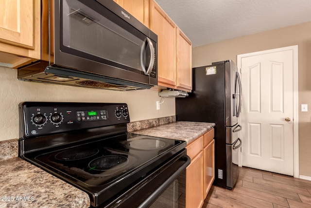 kitchen featuring light brown cabinets, light stone countertops, black electric range oven, and light hardwood / wood-style floors