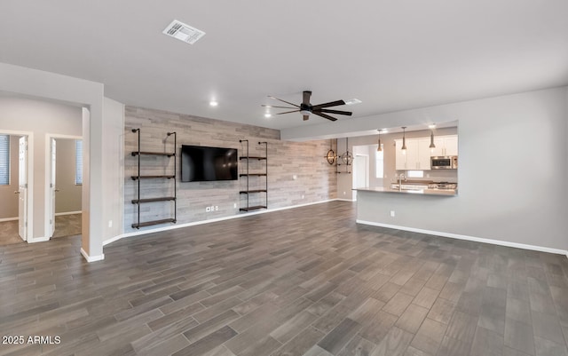 unfurnished living room featuring ceiling fan, sink, and hardwood / wood-style flooring