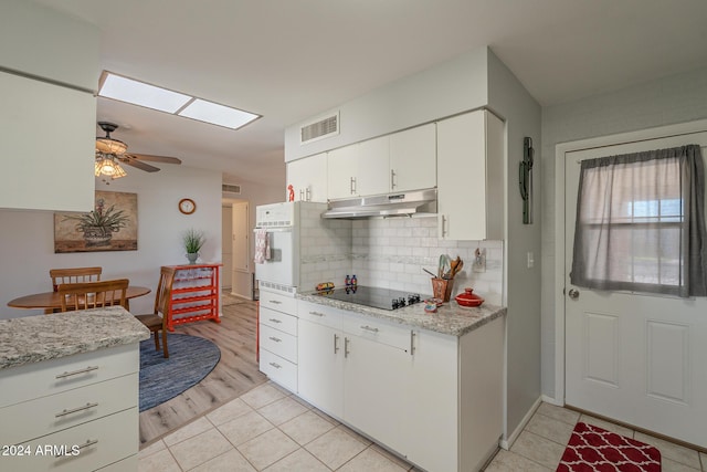 kitchen featuring white oven, white cabinetry, light stone countertops, and light wood-type flooring