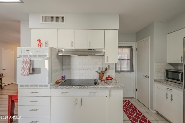 kitchen with white cabinets, white oven, and light hardwood / wood-style floors