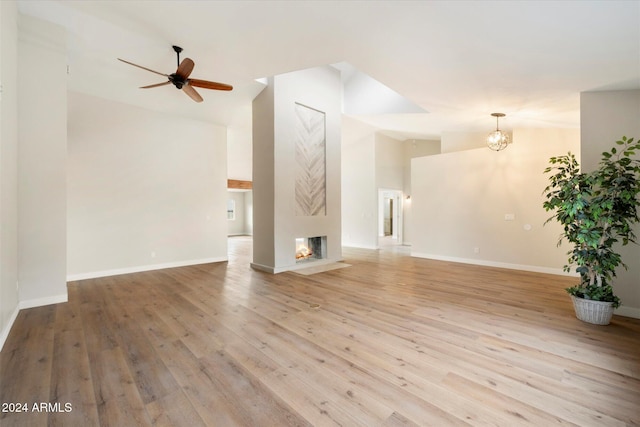 unfurnished living room featuring a multi sided fireplace, light hardwood / wood-style floors, ceiling fan, and lofted ceiling