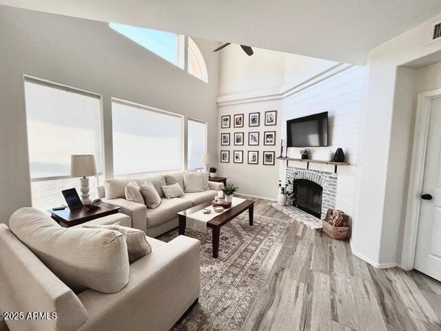 10229 N 12th Ct Unit 1, Phoenix, AZ 85020 - living room with a ceiling fan, wood finished floors, a fireplace, baseboards, and a high ceiling