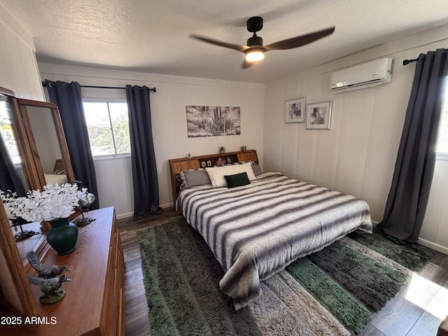 251 W 8th St, Ajo, AZ 85321 - bedroom with a wall mounted air conditioner, dark wood-style floors, a textured ceiling, a ceiling fan, and baseboards