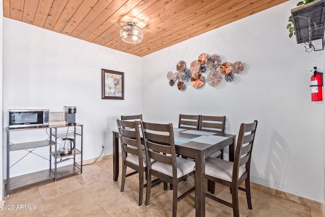 dining space with baseboards and wooden ceiling