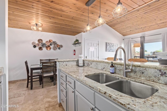 kitchen with light stone countertops, vaulted ceiling, wood ceiling, a sink, and decorative light fixtures