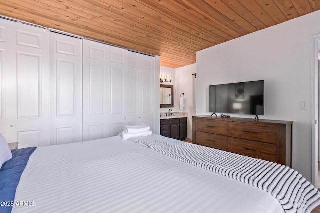 bedroom featuring a sink, a closet, wooden ceiling, and ensuite bath