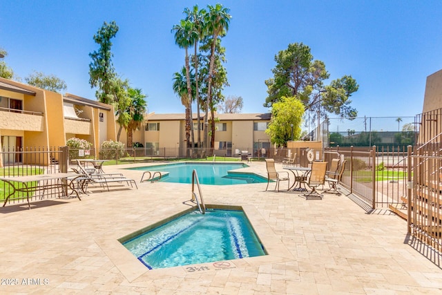 community pool featuring fence, a patio, and a hot tub