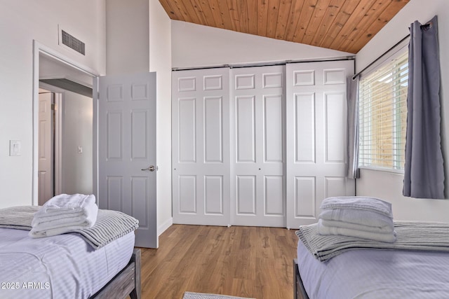 bedroom featuring light wood-style floors, a closet, visible vents, vaulted ceiling, and wooden ceiling