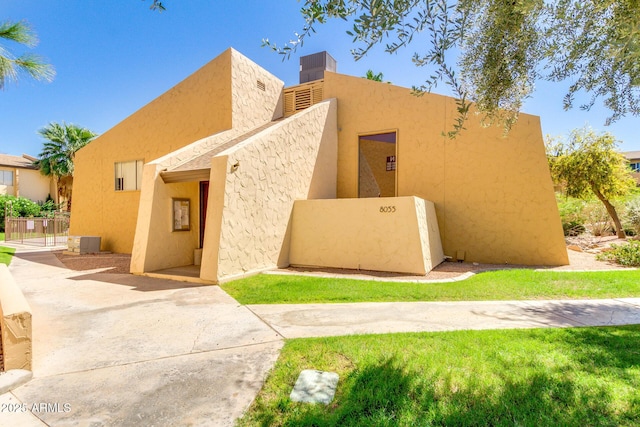 adobe home featuring stucco siding, central AC, and a chimney