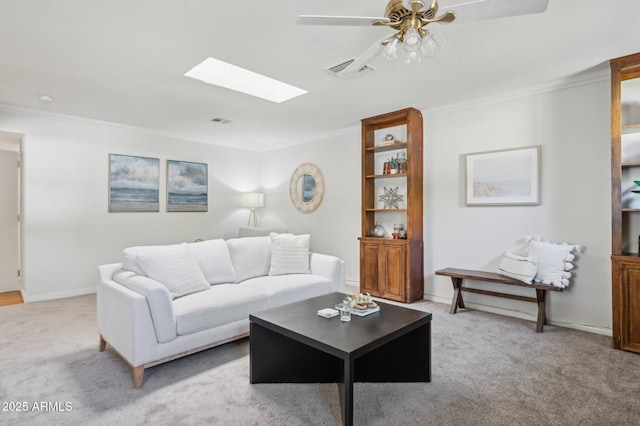 carpeted living room with ornamental molding, ceiling fan, and a skylight