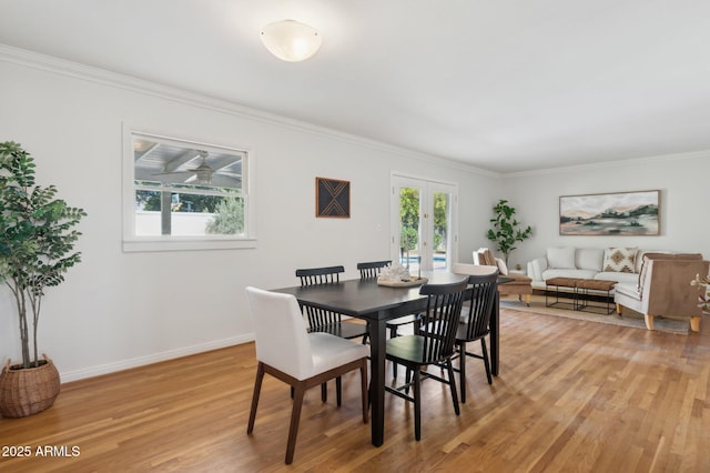 dining area featuring french doors, ornamental molding, a healthy amount of sunlight, and light hardwood / wood-style flooring