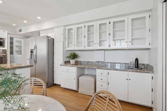 kitchen featuring white cabinetry, appliances with stainless steel finishes, light hardwood / wood-style floors, and light stone counters