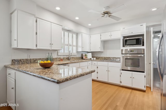 kitchen with white cabinetry, appliances with stainless steel finishes, kitchen peninsula, and sink