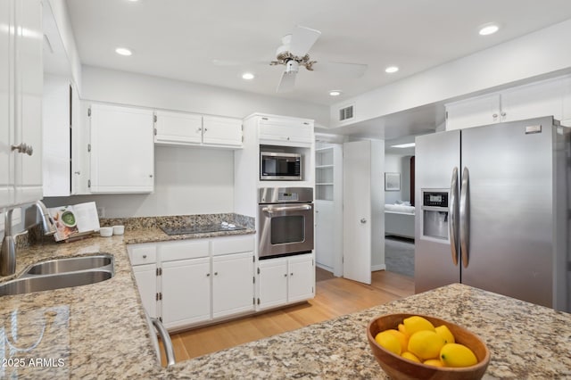 kitchen with white cabinetry, appliances with stainless steel finishes, light stone countertops, and sink