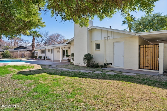 rear view of house with a patio, a fenced in pool, and a lawn