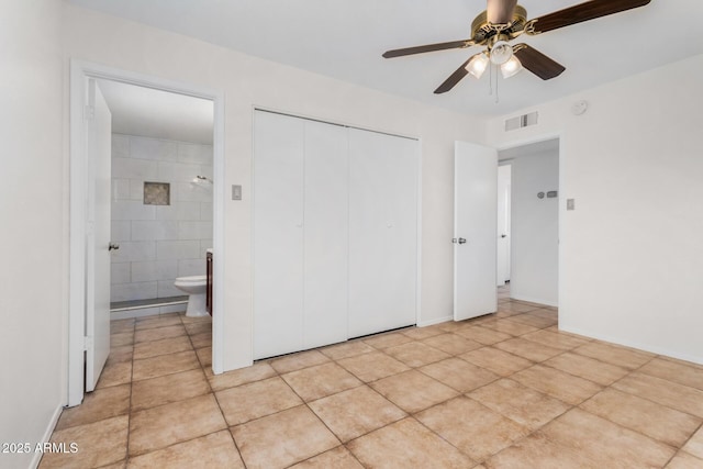 unfurnished bedroom featuring ensuite bathroom, light tile patterned floors, ceiling fan, and a closet