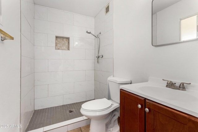 bathroom with vanity, toilet, and a tile shower