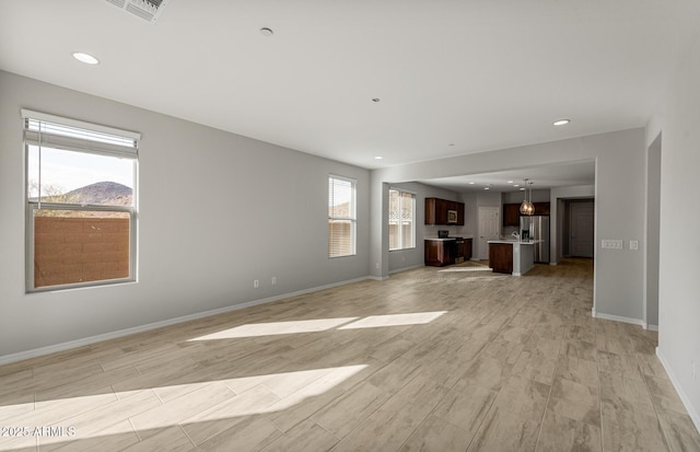 unfurnished living room featuring a mountain view and light hardwood / wood-style floors