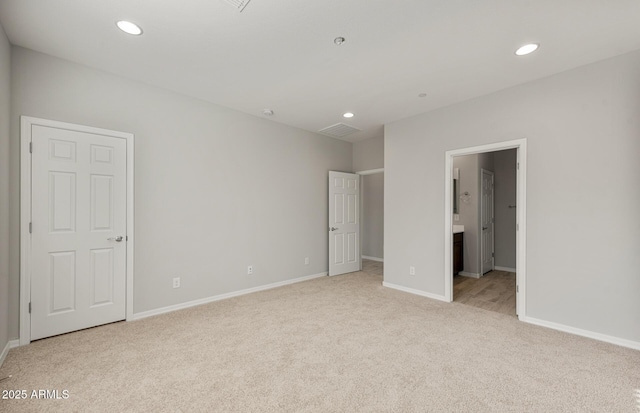 unfurnished bedroom with ensuite bath and light carpet