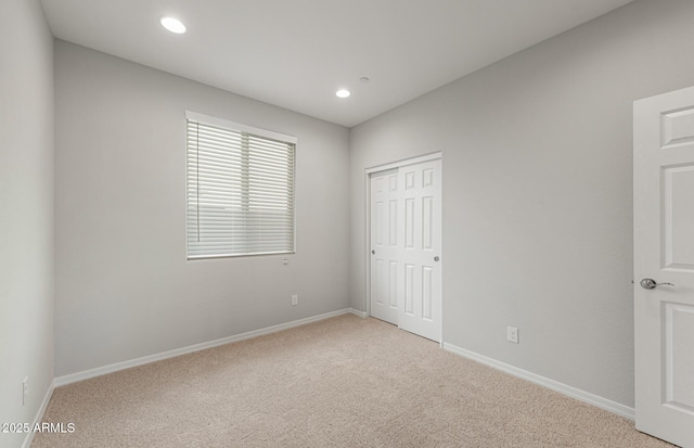 unfurnished bedroom featuring light colored carpet and a closet