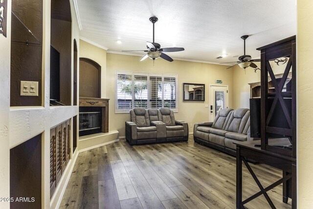 1123 E Shepherds Way, Casa Grande, AZ 85122 - living area with ceiling fan, crown molding, a glass covered fireplace, wood-type flooring, and baseboards
