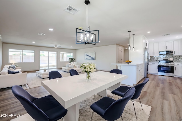 dining space featuring visible vents, light wood-type flooring, and an inviting chandelier