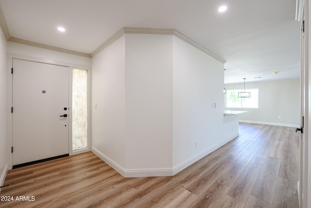 foyer entrance with crown molding, light hardwood / wood-style flooring, and a chandelier