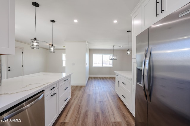 kitchen with white cabinets, appliances with stainless steel finishes, pendant lighting, and light hardwood / wood-style flooring