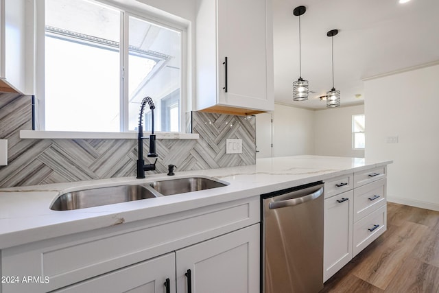 kitchen with decorative light fixtures, decorative backsplash, stainless steel dishwasher, white cabinetry, and a sink