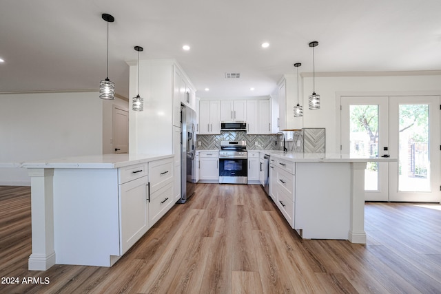 kitchen with light hardwood / wood-style flooring, pendant lighting, appliances with stainless steel finishes, decorative backsplash, and white cabinets