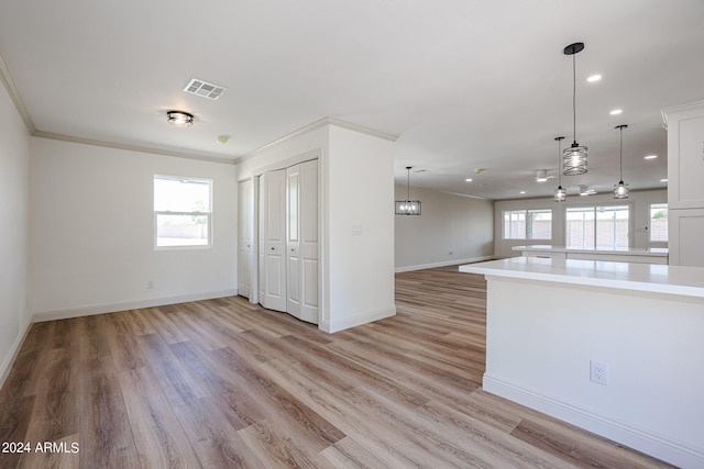 interior space featuring ornamental molding, plenty of natural light, and light hardwood / wood-style flooring