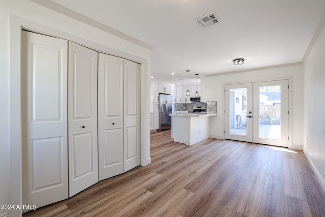 kitchen with decorative light fixtures, light wood-type flooring, appliances with stainless steel finishes, white cabinetry, and kitchen peninsula