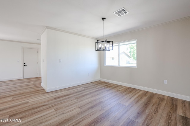 empty room featuring ornamental molding, an inviting chandelier, and light hardwood / wood-style flooring