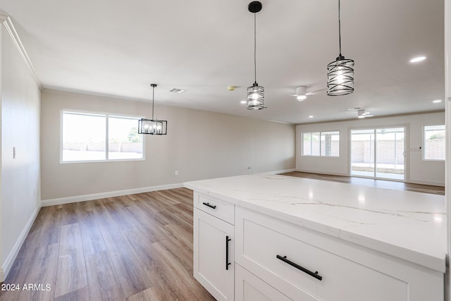 kitchen featuring light wood-type flooring, light stone counters, plenty of natural light, and white cabinetry